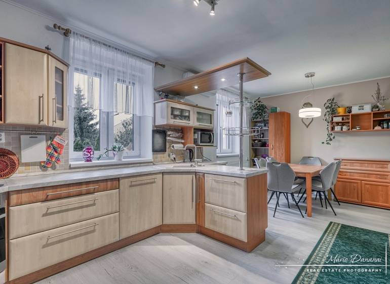 5-izbový rodinný dom s dvomi garážami v obci Špačince - Kuchyňa v rodinnom dome s podlahou s dreveným dekorom, vybavená kuchynským nábytkom.