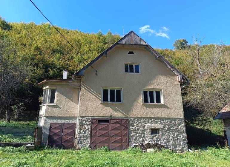 Hospodárska usadlosť  - Rodinný dom v Horných Hámroch v prírode s garážovými dverami a kamennou fasádou.