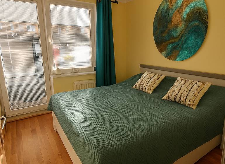 3 izbový byt Zlaté Moravce - Spálňa s podlahou s dreveným dekorom a veľkou posteľou v 3-izbovom byte.