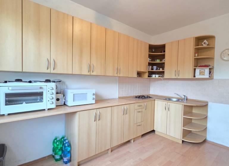 REZERVOVANÉ: NA PREDAJ -  1-izbový byt vo Veľkom Šariši - PREŠOV - Kuchyňa s kuchynskými skrinkami v 1-izbovom byte, vybavená spotrebičmi a podlahou s dreveným dekorom.