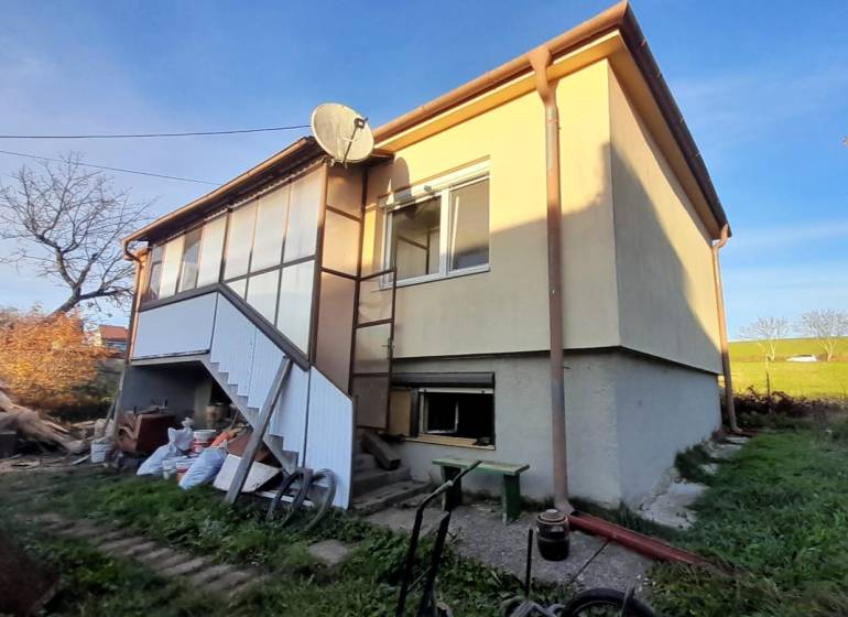 Rodinný dom v obci Dobrá Voda  - Rodinný dom v Dobrá Voda so schodiskom, záhradou a satelitnou anténou na dvore.