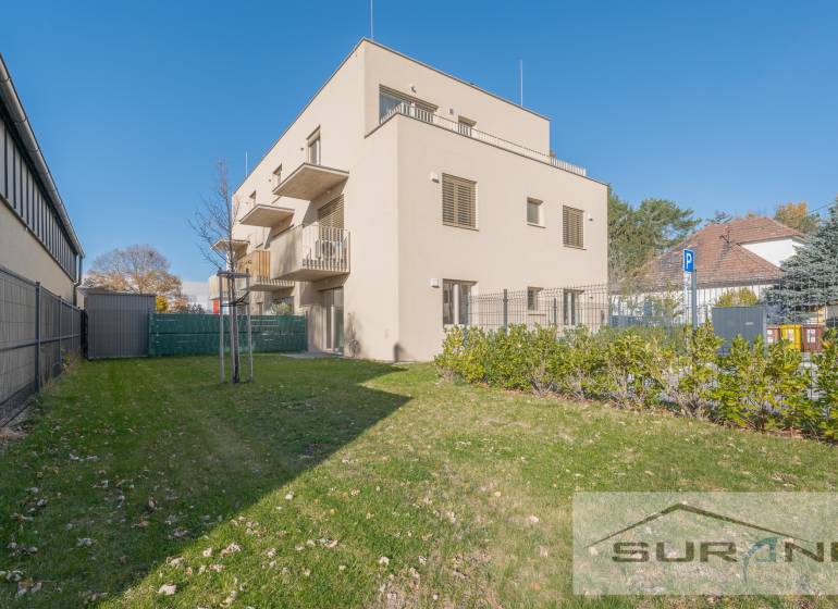 2-izbový byt s predzáhradkou 135 m² a parkovaním v tichej časti BA - Budova s dvomi poschodiami, zelená tráva a modrá obloha na Železničnej ulici v Bratislave.