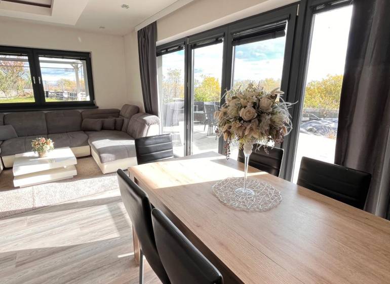 Rodinný dom v obci Dubová s 920m2 rozsiahlym pozemkom  - Obývačka rodinného domu s podlahou s dreveným dekorom a komfortným sedením.