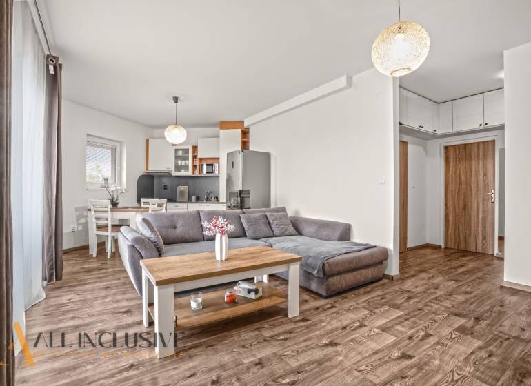 NA PREDAJ 2-IZBOVÝ BYT S 2 BALKÓNMI, DUNAJSKÁ STREDA - Obývacia izba 2-izbového bytu s pohovkou a podlahou s dreveným dekorom.