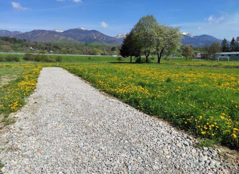 TURANY-Stavebný pozemok 950m2 so sieťami cena v RK - Štrkova cesta vedie cez pole plné púpav s horami v pozadí. Pozemky - bývanie.