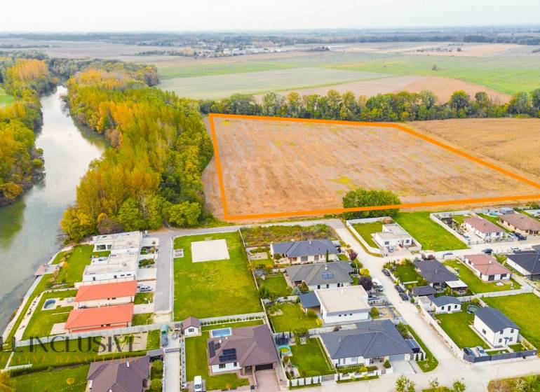 NA PREDAJ INVESTIČNÝ STAVEBNÝ POZEMOK, JAHODNÁ - Krajina v Jahodnej s developerskými pozemkami pri rieke a blízkymi domami.