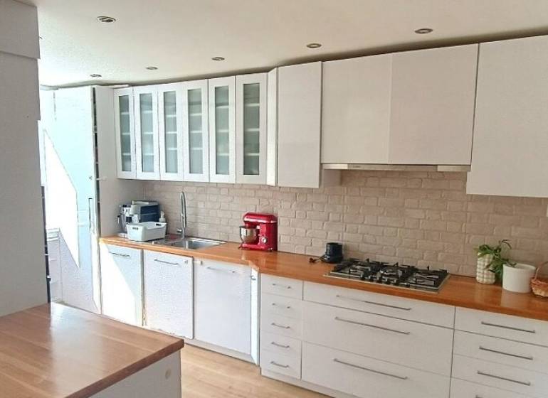 Elegantný 3 izbový byt (78 m²) s 2 balkónmi po kompletnej rekonštrukci - Kuchyňa v 3-izbovom byte s bielym nábytkom a sporákom, podlaha s dreveným dekorom.