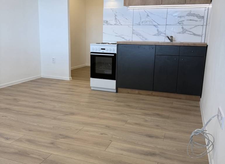  Prenájom garsónky po kompletnej rekonštrukcii (možnosť odkúpenia) - Garsónka s kuchynskou linkou, sporákom a podlahou s dreveným dekorom.
