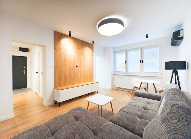 Prenájom úplne nového 2 izb. bytu - skvelá poloha a komfortné bývanie. - Obývacia izba s pohovkou, jedálenským stolom, dreveným dekorom podlahy v 2-izbovom byte.