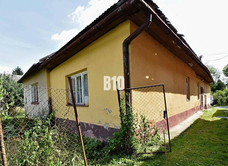 Rodinný dom s veľkým pozemkom o výmere 3271m2  na predaj - Rodinný dom v Partizánskej Ľupči, žltá fasáda, starý plot s pletivom.