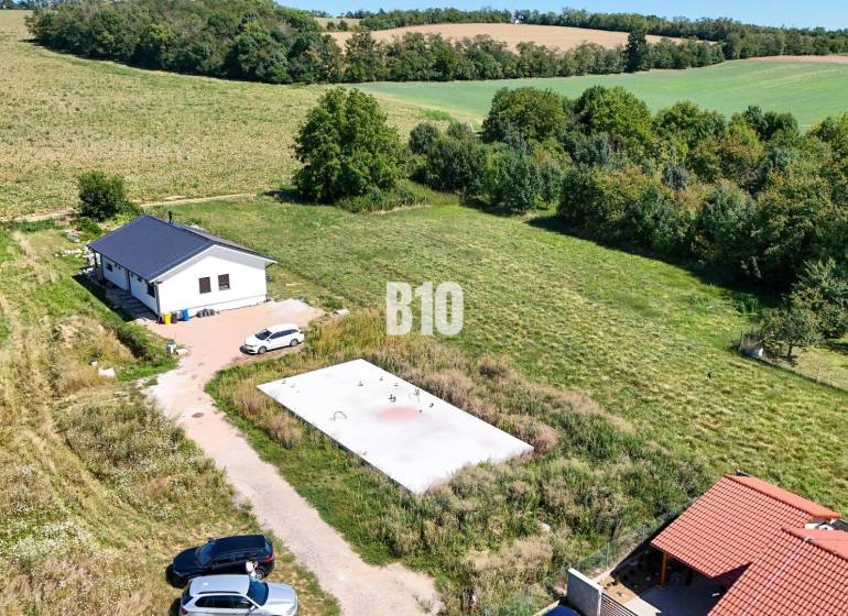 Základová doska na  575 m2 pozemku - Čeľadice - Záber na pozemok pre bývanie v Čeľadiciach zahŕňa dom, zeleň a autá.