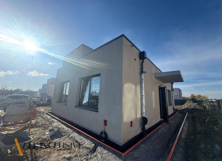 NA PREDAJ 4-IZBOVÝ RODINNÝ DOM (ČASŤ DVOJDOMU), HUBICE - Exteriér rodinného domu v Hubiciach počas výstavby, slnečné počasie zosvetľuje scénu.