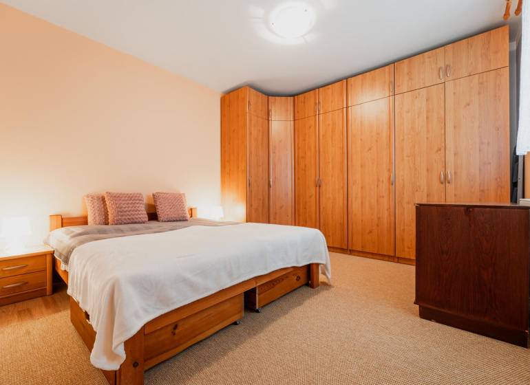 VÝBORNÁ CENA  3 izbový byt Armádna ulica v Trenčíne  - Spálňa v 3-izbovom byte s posteľou, vstavanou skriňou a podlahou s dreveným dekorom.