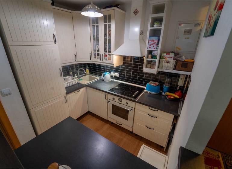 Na predaj útulný 2 izbový byt so zahradkou Svätý Jur 165.000,- Eur - Kuchyňa v 2-izbovom byte s svetlými skrinkami a podlahou s dreveným dekorom.