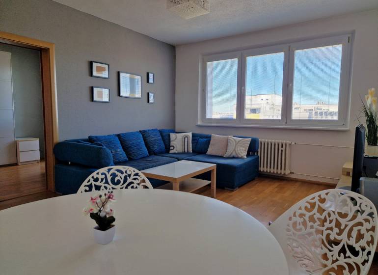 PRENÁJOM zariadený 3-izb byt, Pribišova, Bratislava - Obývačka 3-izbového bytu so sedačkou, bielym stolom a podlahou s dreveným dekorom.