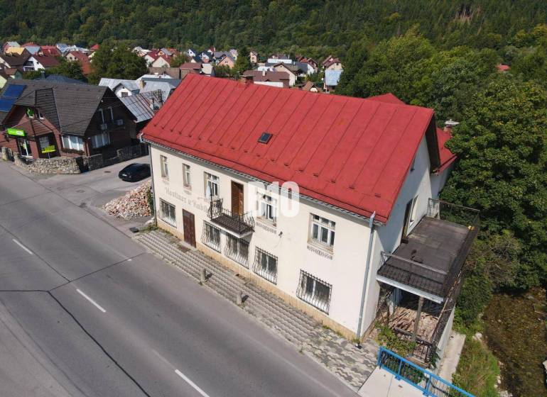 Teraz zľava 30.000 TOP INVESTIČNÁ PRÍLEŽITOSŤ Polyfunkčný objekt na pr - Budova v Belej s červenou strechou, okolité domy a príroda.