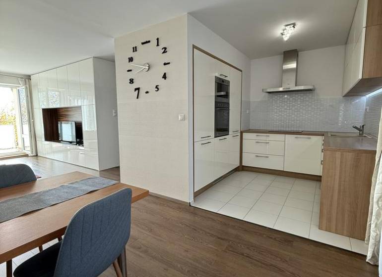 Novinka: Moderný  4-izb. mezonetový byt s balkónom a terasou. Muškát - Jedálenský priestor v 4-izbovom byte s podlahou s dreveným dekorom a kuchyňou v pozadí.