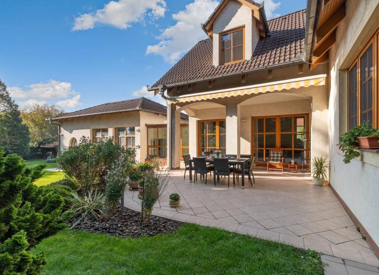 Predaj luxusná 5 izbová Vila,440 m2,pozemok 1061m2,garáž,bazén. - Vila na ulici Hrušovská s terasou, záhradkou, obdĺžnikovým stolom a stoličkami pod markízou.