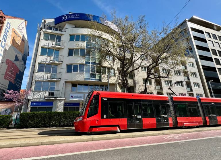 Obchodno- kancelársky priestor s výkladom na Nám. slobody - Na ulici Námestie slobody stojí červená električka pred kanceláriami.