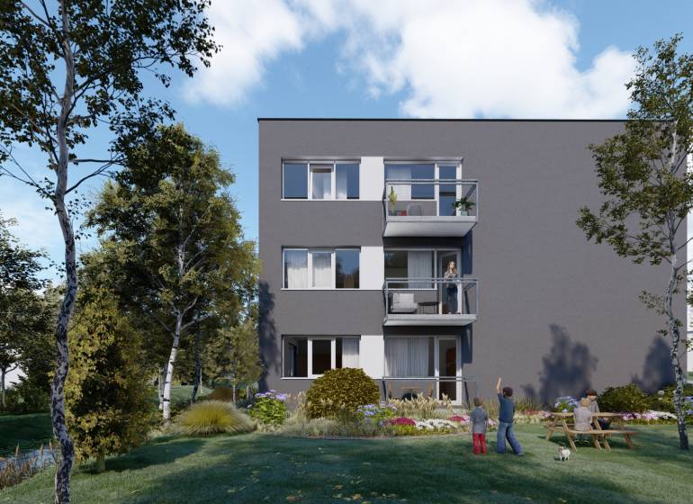 Pozemok s rozostavanou stavbou pre 12 bytov pri Senici - Bytová budova s balkónmi obklopená stromami, trávnikom a ľuďmi v záhrade.