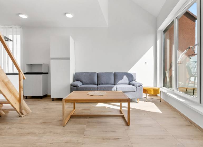 OPAL - NOVÝ a KOMPLETNE ZARIADENÝ 2,5-izbový byt s LODŽIOU a PARKOVANÍ - Obývačka v 2-izbovom byte s pohovkou, stolíkom a podlahou s dreveným dekorom.