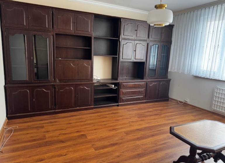 Prenájom 3izb. zariadeného bytu na Jazdeckej ul., Nové Zámky - Obývacia izba v 3-izbovom byte s podlahou s dreveným dekorom, tmavý nábytok.