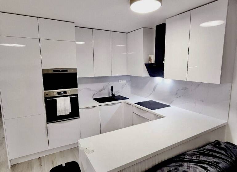 PREDAJ - 3-izbový veľkometrážny byt v RED OAK, Lužianky - REZERVOVANÉ - Kuchyňa s bielymi skrinkami a podlahou s dreveným dekorom v 3-izbovom byte.