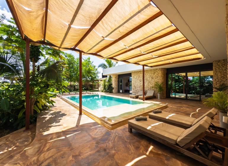 LUXURY 2-BEDROOM VILLA IN PAJE - Záhrada rodinného domu na ulici Paje v Unguja South Region s bazénom a lehátkami.