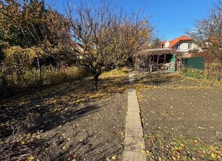 Apartim predá záhradu s možnosťou výstavby na Strednej ul v Ružinove - Jesenná záhrada na Strednej ulici v Bratislave-Ružinove s chodníkom a stromami.