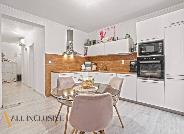 NA PREDAJ 3-IZB. BYT S TERASOU A ZÁHRADKOU, DUN.STREDA - Kuchyňa v 3-izbovom byte s bielymi skrinkami, podlahou s dreveným dekorom a jedálenským stolom.