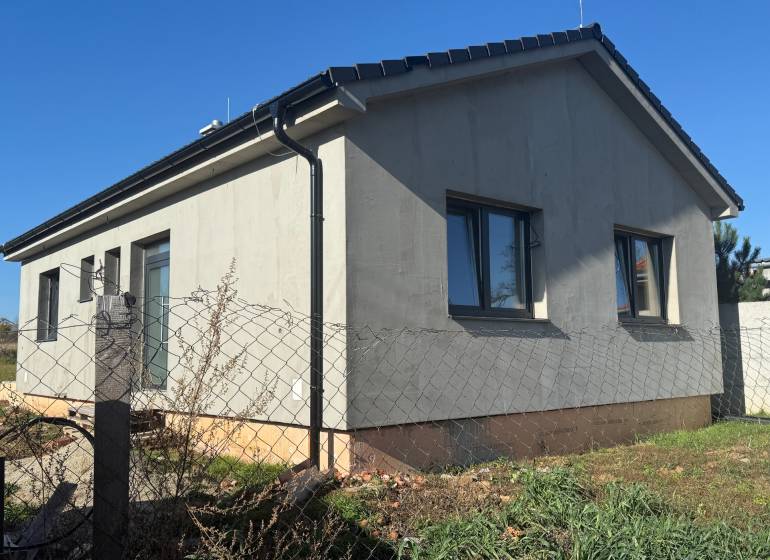 PREDAJ - NOVOSTAVBA - TESÁRSKE MLYŇANY - Rodinný dom v Tesárskych Mlyňanoch so sivou fasádou a oknami, oplotený plotovým pletivom.