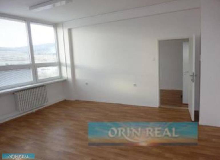 PRENÁJOM KANCELÁRSKÝCH PRIESTOROV NA RAČIANSKEJ ULICI - Svetlá miestnosť s veľkým oknom, drevenou podlahou a radiátorom v lokalite Račianska.