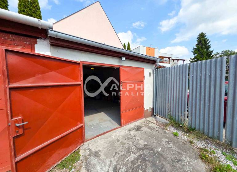 Prenájom garáž, centrum, Spišská Nová Ves - Otvorené garáže v Spišskej Novej Vsi s červenými dverami a plechovým plotom.