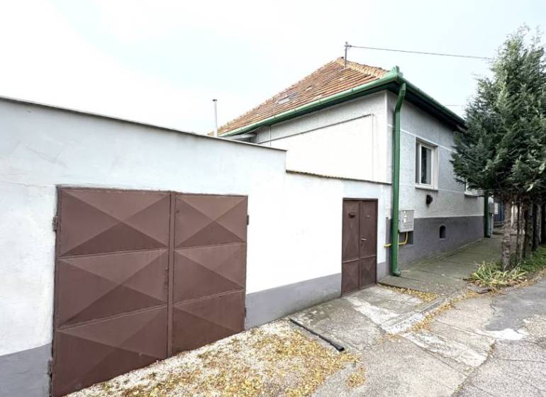 IBA U NÁS !!! ponúka EXKLUZÍVNE na predaj rodin - Rodinný dom v Komárne so zelenými detailami a hnedou bránou na tichej ulici.