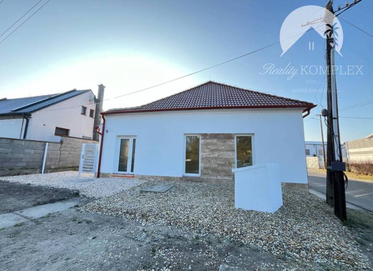 Vám ponúka  na predaj budovu na BÝVANIE aj PODN - Dom s bielou fasádou, šikmou strechou, oknami a bielym kamienkovým chodníkom pred ním.