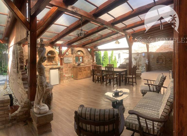 Vám ponúka do PRENÁJMU čarovný, úplne zrekonštr - Krytá terasa v rodinnom dome s tehlovou stenou, drevenými trámami a podlahou s dreveným dekorom.