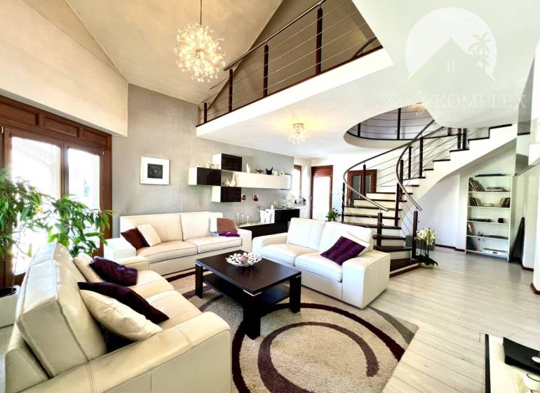 Ponúka na PREDAJ zrekonštruovaný 5 izbový podpi - Obývacia izba v rodinnom dome so špirálovým schodiskom a bielym nábytkom.