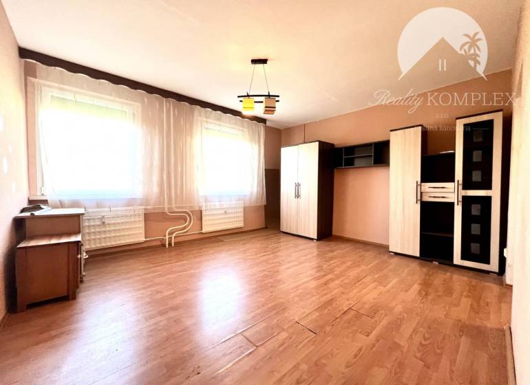 Ponúka na PREDAJ 1 izbový byt v Komárne - Svetlá izba v 1-izbovom byte s policovou skriňou a podlahou s dreveným dekorom.