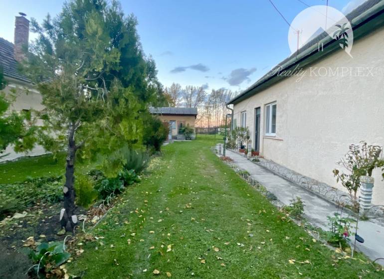 Investičný pozemok s obývateľným domom vo Vrakúni - Rodinný dom vo Vrakúni s udržiavanou záhradou, popri dome vedie chodník.