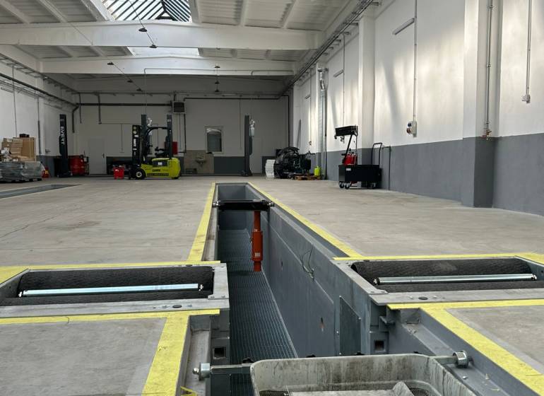 Autoservis s výbavou pre vozidlá v uzavretom priemyselnom areáli - HC - Priemyselný priestor s nabíjacou stanicou, technikou a svetlíkom v budove.