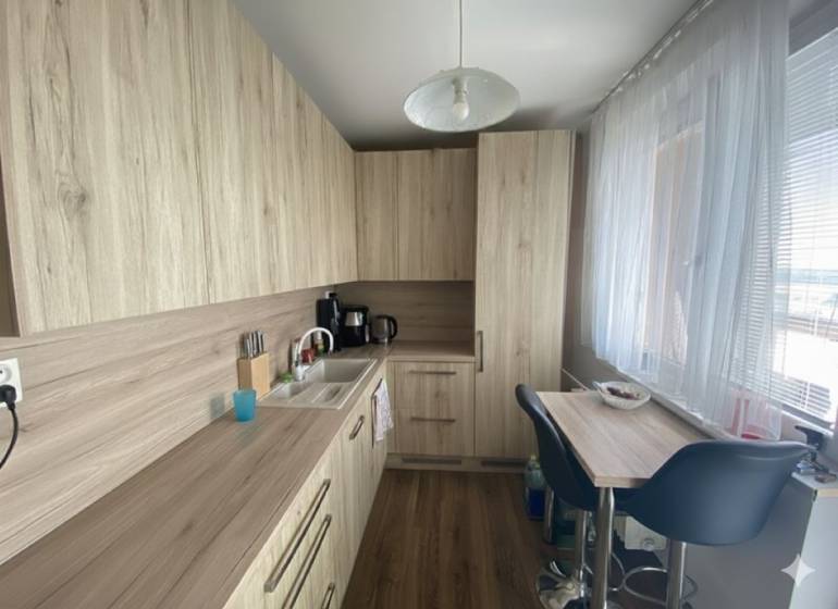 Exkluzívne v našej RK 3 izbový byt po rekonštrukcii s dvomi loggiami - Kuchyňa v 3-izbovom byte s podlahou s dreveným dekorom a svetlým nábytkom.