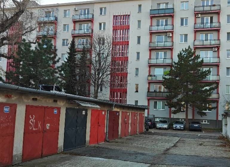 Garáž, Haburská ul., Ružinov pri Štrkovci - Garáže na Haburskej ulici, Bratislava - Ružinov, pred bytovým domom s červenými detailmi.