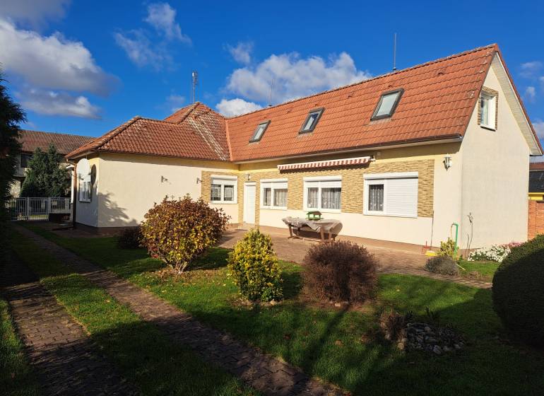 REZERVOVANÉ! Predáme 4-izb. rodinný dom, pozemok 1414 m2, Vráble - Rodinný dom na Bernolákovej ulici vo Vrábľoch, obklopený zelenou záhradou a modrou oblohou.