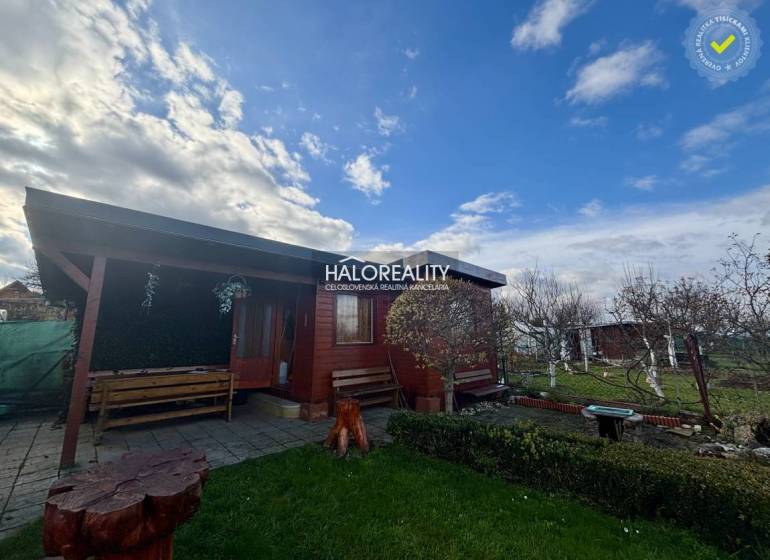 Predaj, záhradný pozemok   231 m2 Spišská Nová Ves, ... - Drevená chatka v záhradách Spišskej Novej Vsi s lavičkami a kvetinovým záhonom.