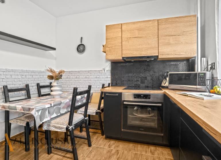 NA PREDAJ 3-IZBOVÝ BYT S PIVNICOU, SENEC - Kuchyňa s dreveným dekorom, jedálenským stolom a spotrebičmi v 3-izbovom byte.