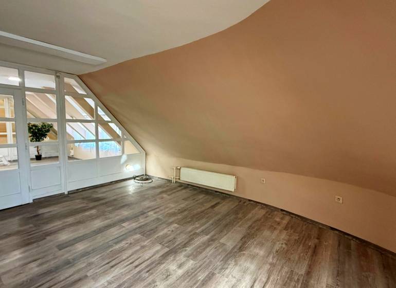 Na predaj unikátna dvojpodlažná budova na podnikanie aj bývanie - Interiér budovy s podlahou s dreveným dekorom a šikmou svetlohnedou stenou.