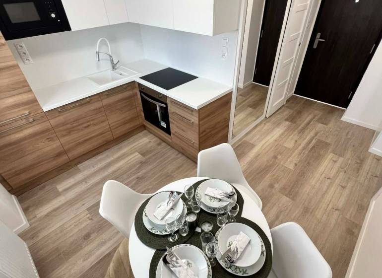 PREDAJ: 2 izbový tehlový byt-komplet.rek. - KOMÁRNO - Kuchyňa v 2-izbovom byte s podlahou s dreveným dekorom a jedálenským stolom.