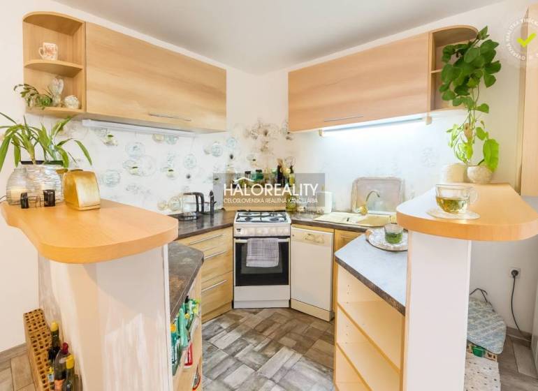 Predaj, rodinný dom Komárno, štvorizbový, čiastočná ... - Kuchyňa v rodinnom dome s rohovou linkou a dreveným dekorom, dekoratívnymi rastlinami na poličkách.