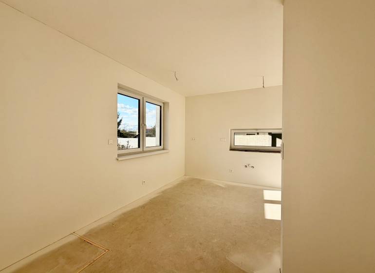 NOVOSTAVBA  ATRAKTÍVNY 4 I RODINNÝ DOM,650m2 pozemok - Prázdna izba s dvojitým oknom a betónovou podlahou v rodinnom dome.