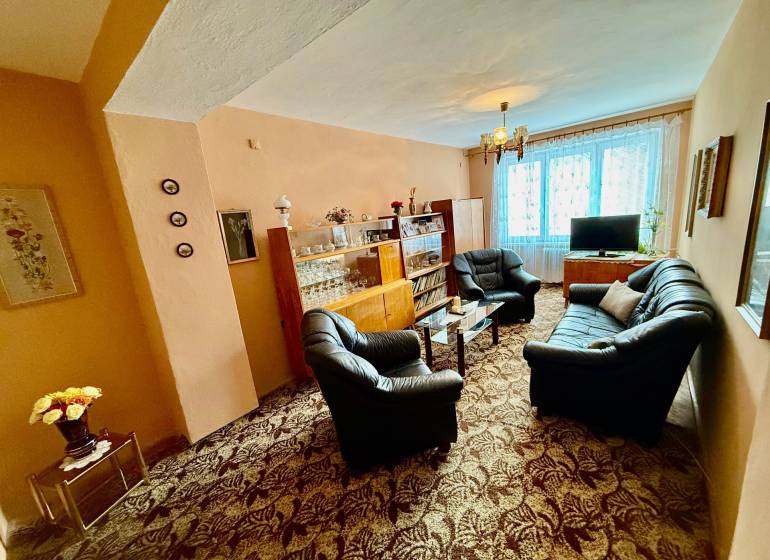 Dvojizbový byt v pôvodnom stave, Považská Bystrica - Obývačka v 2-izbovom byte so sedacou súpravou a presklenou vitrínou.